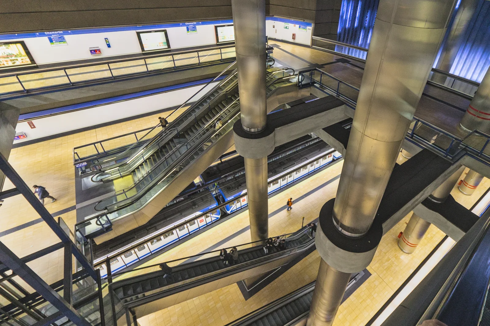 Andenes de Metro en Chamartín, con escaleras mecánicas entre niveles y un tren